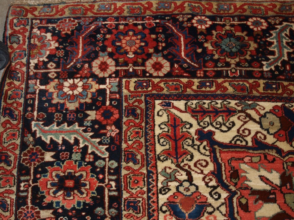 A large hand-knotted Persian Heriz wool carpet featuring a bold central geometric medallion in rust red, dark indigo, and ivory tones. View II