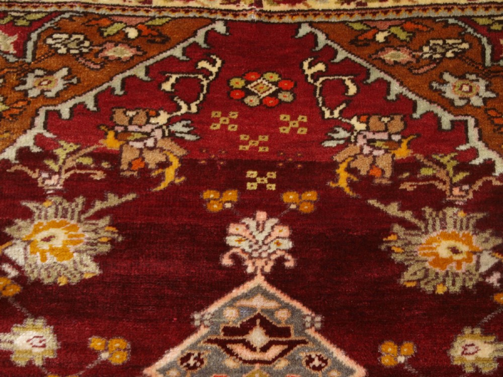 An antique hand-knotted Turkish Avanos wool rug featuring a deep burgundy red field with a central geometric medallion and cream floral border. View VIII