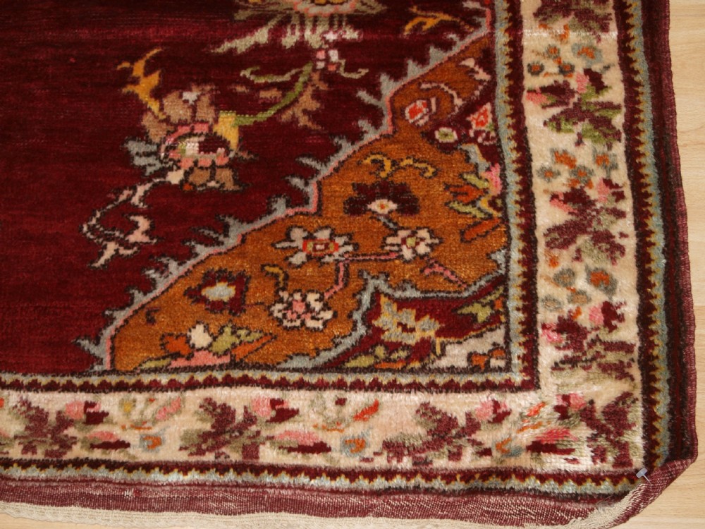 An antique hand-knotted Turkish Avanos wool rug featuring a deep burgundy red field with a central geometric medallion and cream floral border. View IX