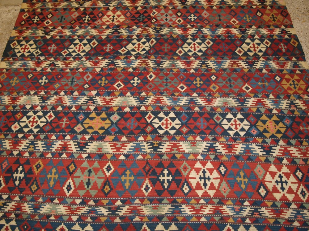 An antique flatweave wool kilim featuring horizontal bands filled with geometric diamond and cross motifs in red, navy blue, ivory, and yellow tones. View VI