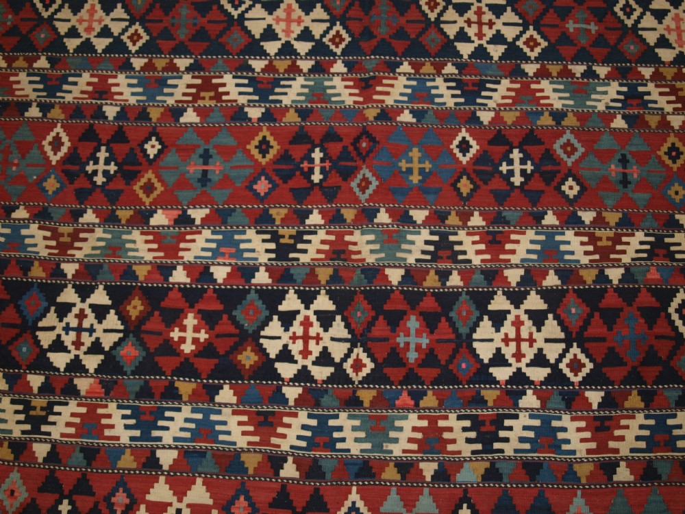 An antique flatweave wool kilim featuring horizontal bands filled with geometric diamond and cross motifs in red, navy blue, ivory, and yellow tones. View VIII
