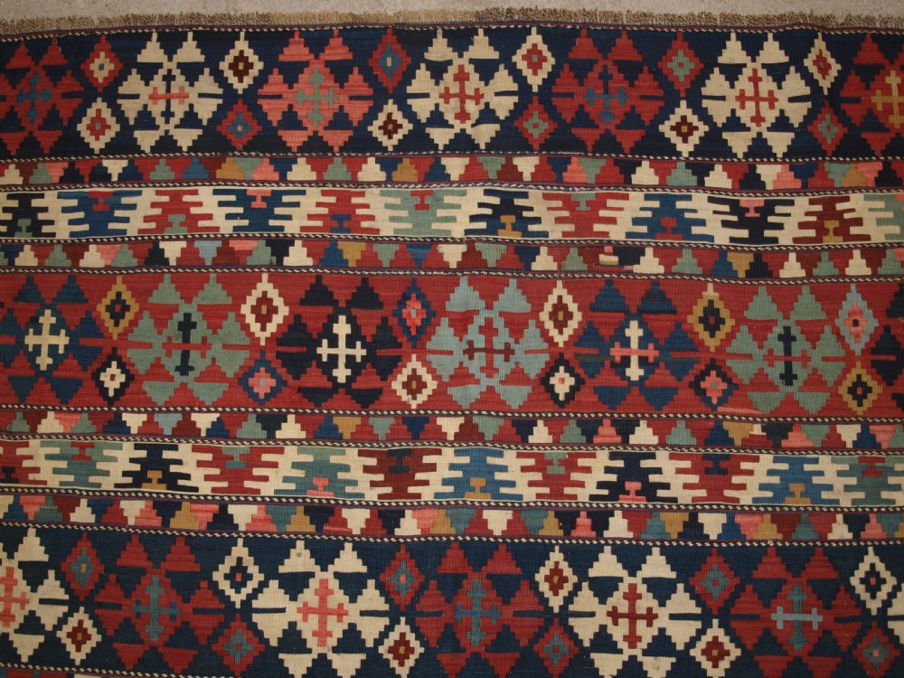 An antique flatweave wool kilim featuring horizontal bands filled with geometric diamond and cross motifs in red, navy blue, ivory, and yellow tones. View IX