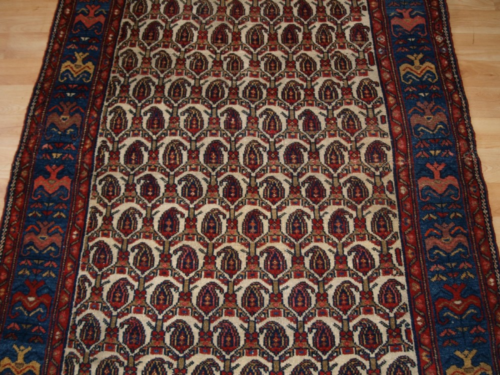 An antique Hamadan hand-knotted wool rug featuring a repeating boteh pattern on an ivory field surrounded by a deep blue border with stylized motifs. View VI