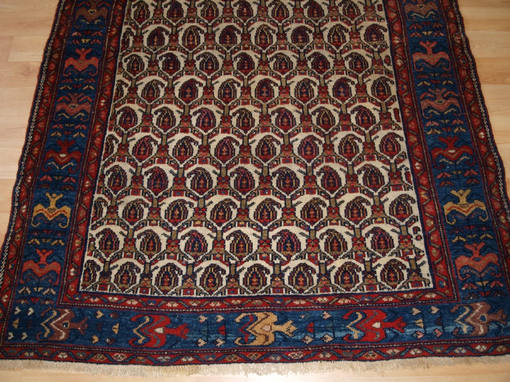 An antique Hamadan hand-knotted wool rug featuring a repeating boteh pattern on an ivory field surrounded by a deep blue border with stylized motifs. View VIII