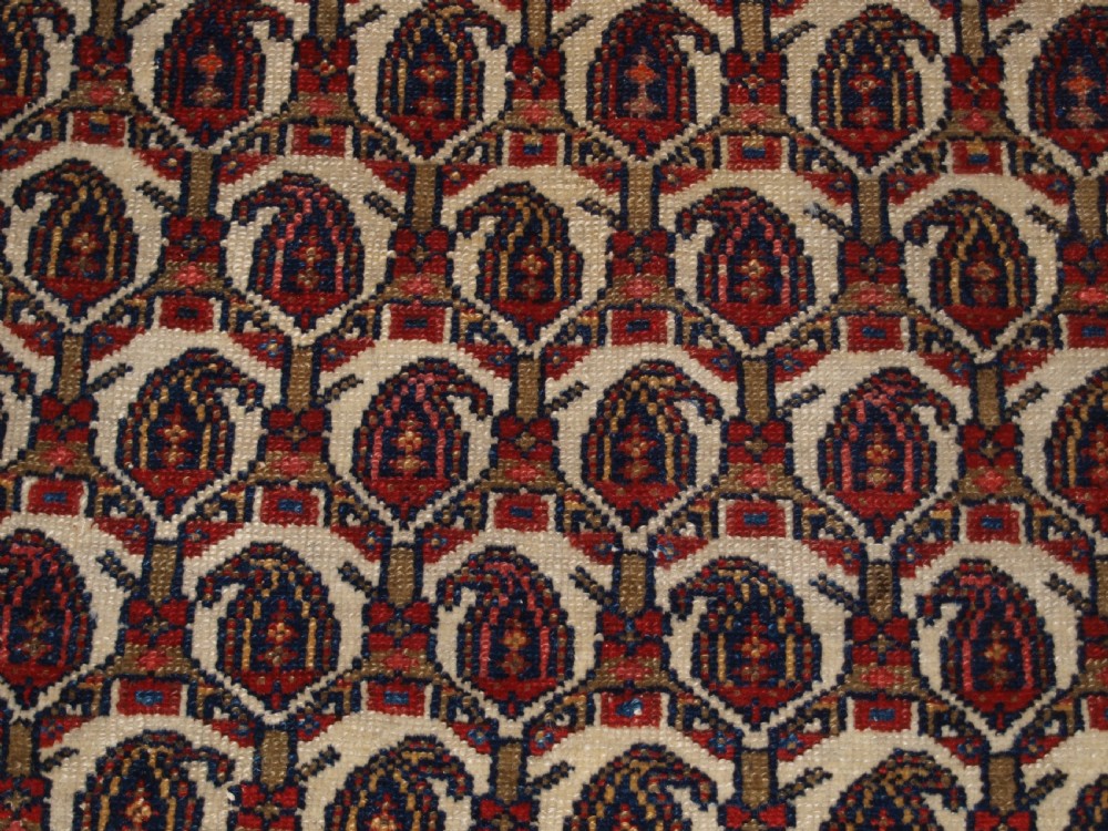 An antique Hamadan hand-knotted wool rug featuring a repeating boteh pattern on an ivory field surrounded by a deep blue border with stylized motifs. View IX