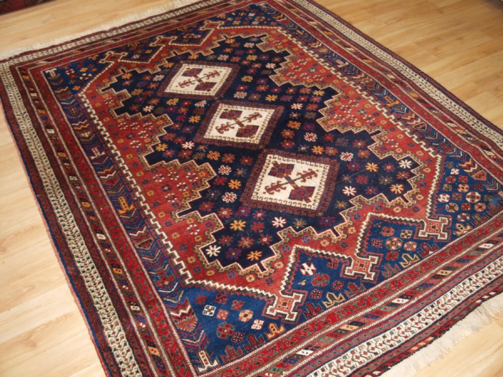 A hand-knotted antique Persian Afshar rug featuring three stacked diamond medallions surrounded by geometric floral motifs in navy blue, terracotta red, and ivory tones. View II