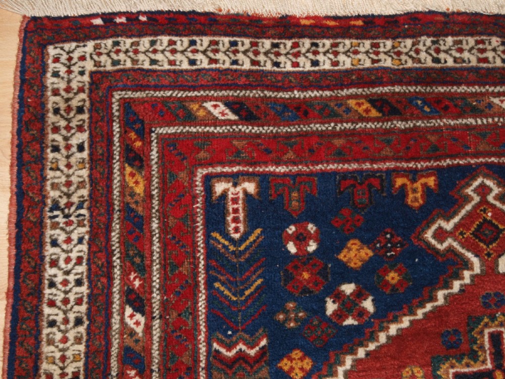 A hand-knotted antique Persian Afshar rug featuring three stacked diamond medallions surrounded by geometric floral motifs in navy blue, terracotta red, and ivory tones. View III