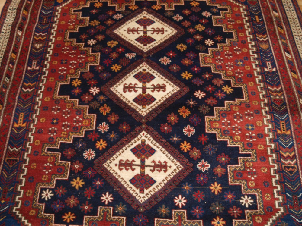 A hand-knotted antique Persian Afshar rug featuring three stacked diamond medallions surrounded by geometric floral motifs in navy blue, terracotta red, and ivory tones. View VI