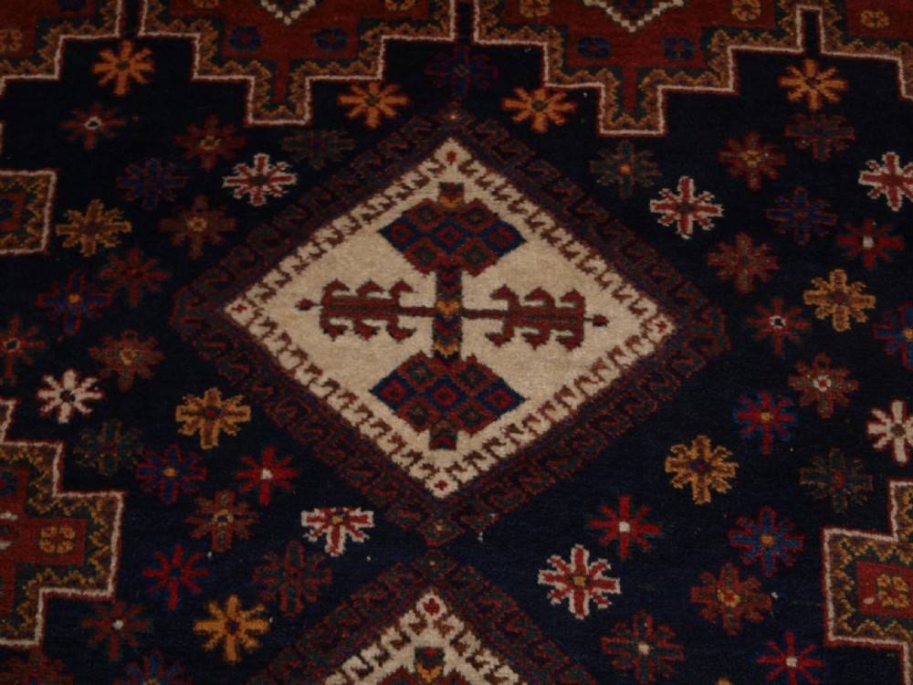 A hand-knotted antique Persian Afshar rug featuring three stacked diamond medallions surrounded by geometric floral motifs in navy blue, terracotta red, and ivory tones. View IX