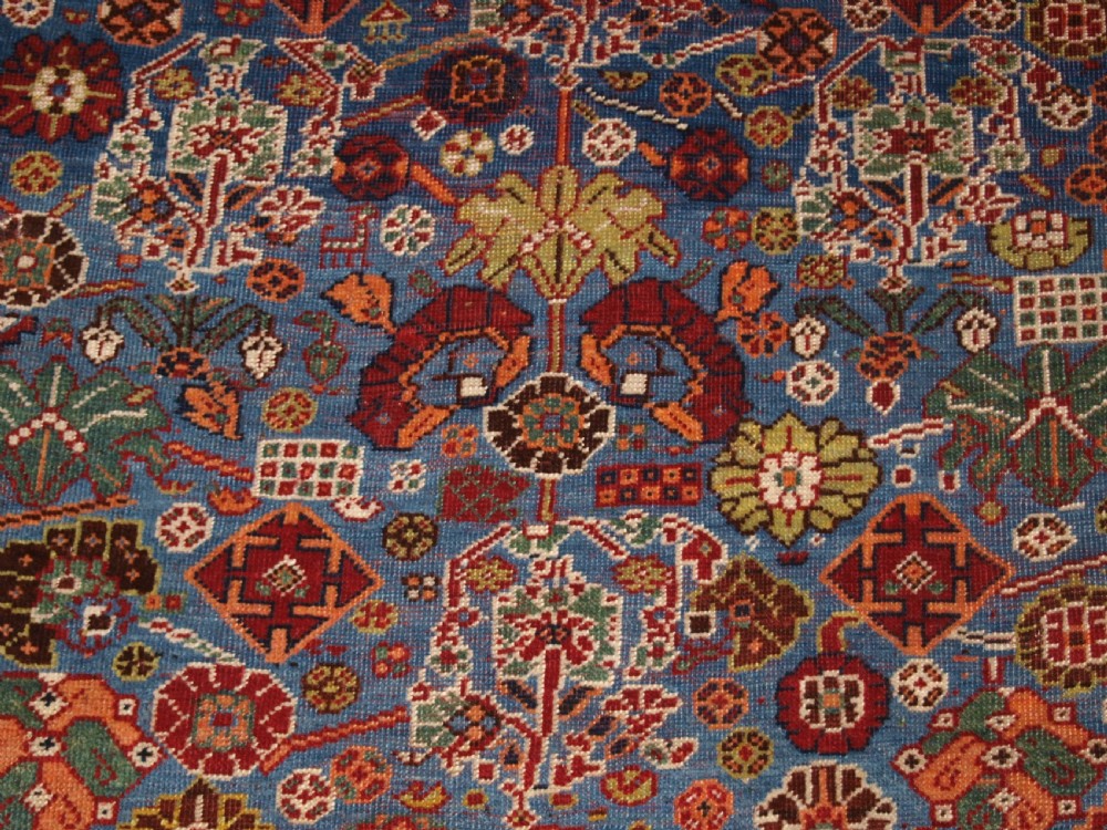 An antique hand-knotted Qashqai Persian rug featuring a central blue field filled with red, white, and yellow geometric tribal motifs framed by a multi-stripe border. View VIII