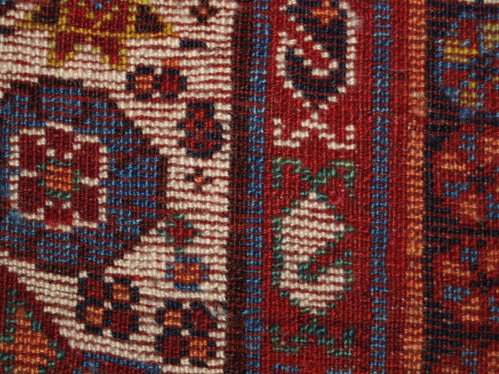 An antique hand-knotted Qashqai Persian rug featuring a central blue field filled with red, white, and yellow geometric tribal motifs framed by a multi-stripe border. View XIII