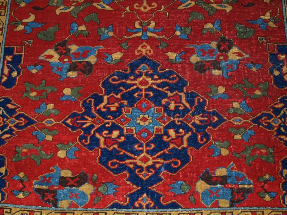 An antique hand-knotted Turkish Ushak carpet featuring a crimson red field decorated with large navy blue star medallions and detailed geometric borders. View IX