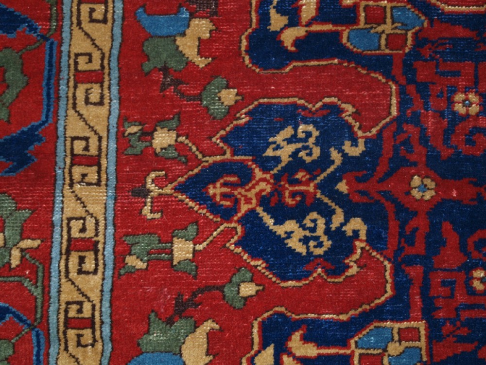 An antique hand-knotted Turkish Ushak carpet featuring a crimson red field decorated with large navy blue star medallions and detailed geometric borders. View XIV