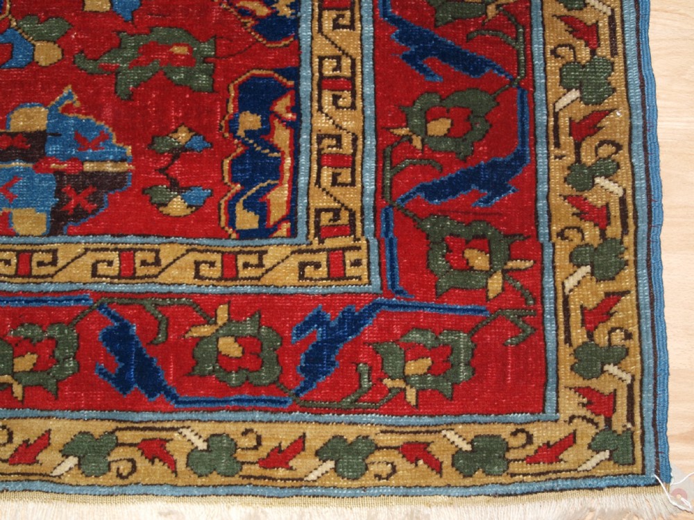 An antique hand-knotted Turkish Ushak carpet featuring a crimson red field decorated with large navy blue star medallions and detailed geometric borders. View XVIII