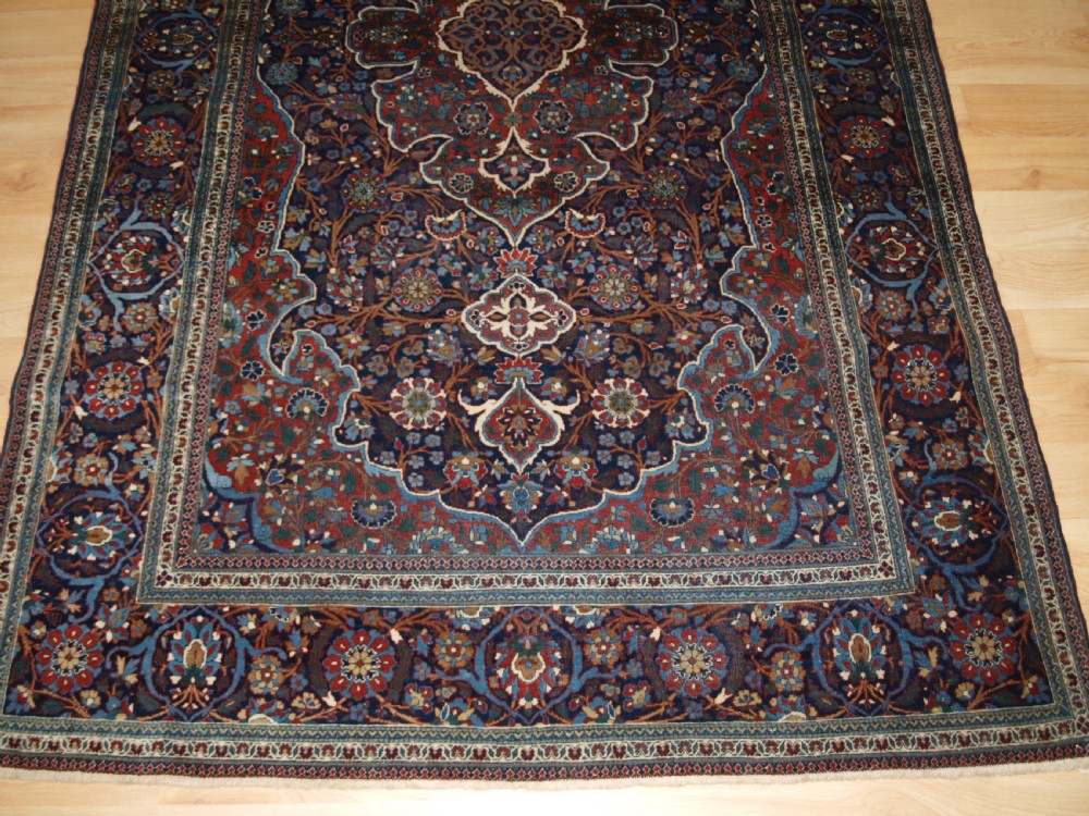 A hand-knotted Persian Kork Kashan wool rug featuring a central medallion with intricate floral motifs in navy blue, red, and cream. View VI