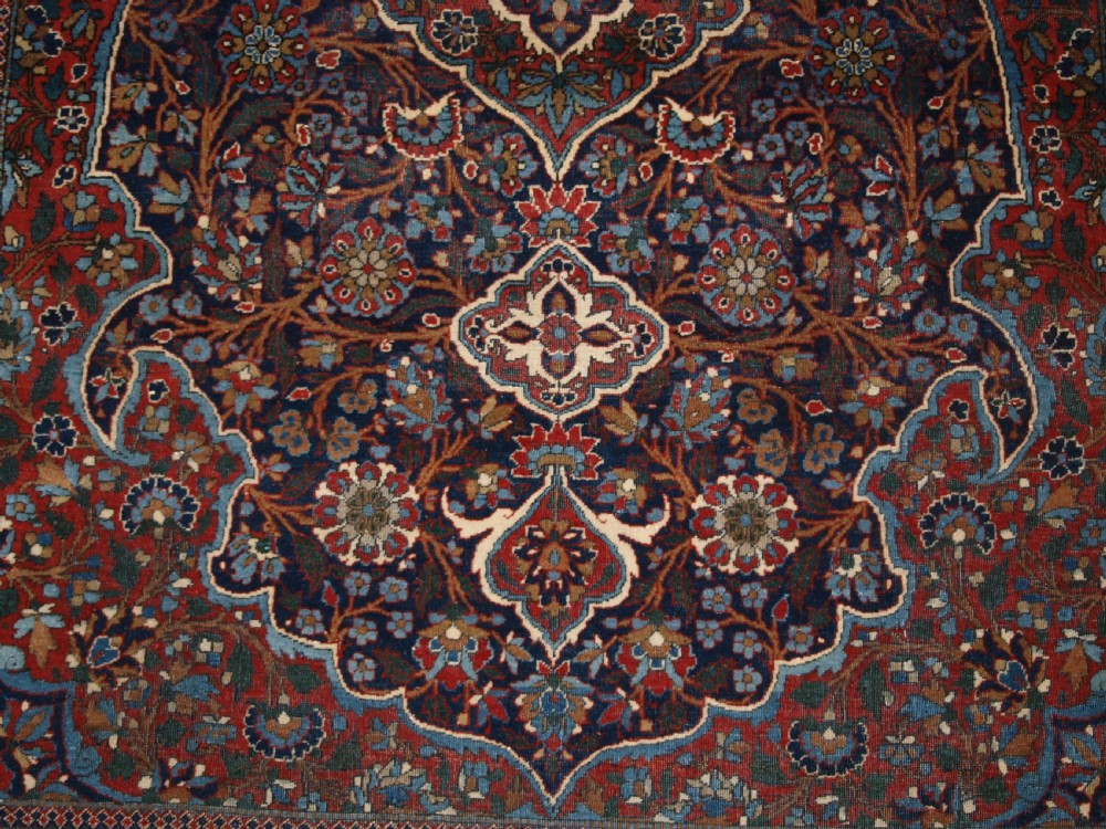 A hand-knotted Persian Kork Kashan wool rug featuring a central medallion with intricate floral motifs in navy blue, red, and cream. View X