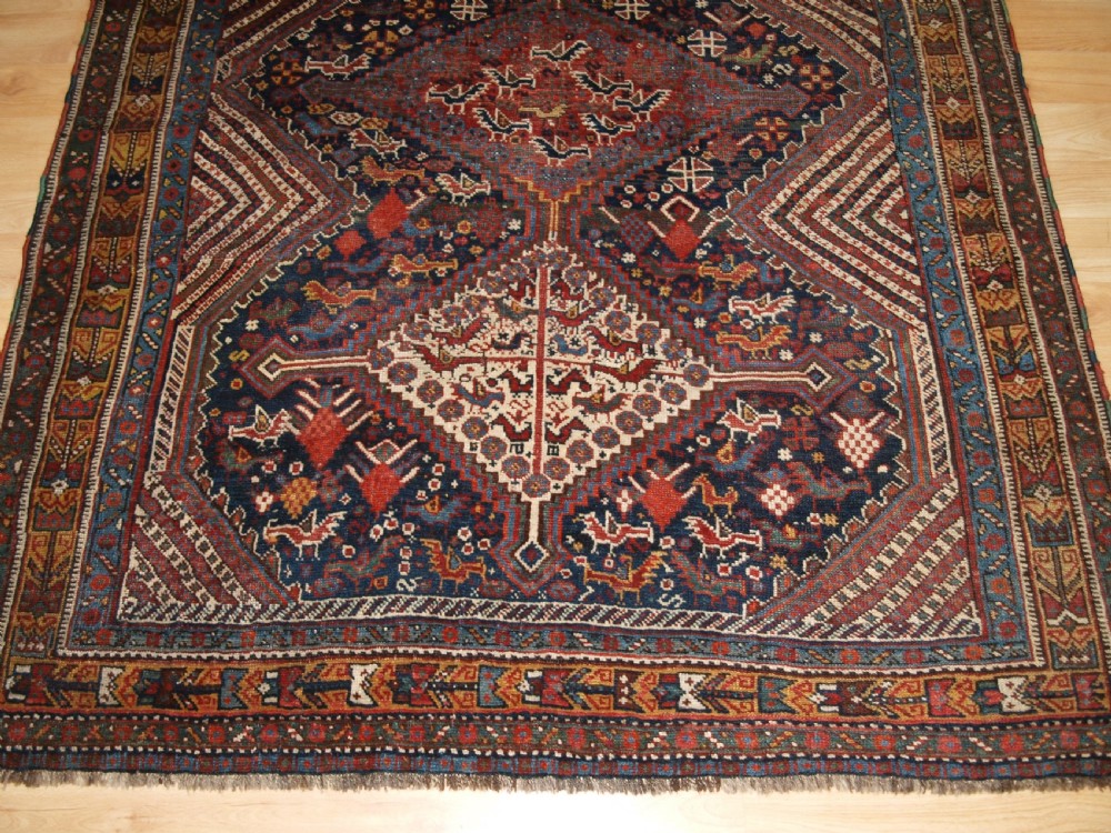 An antique hand-knotted Persian Khamseh wool rug featuring triple diamond medallions filled with stylized bird motifs on a dark navy and red geometric field. View VI