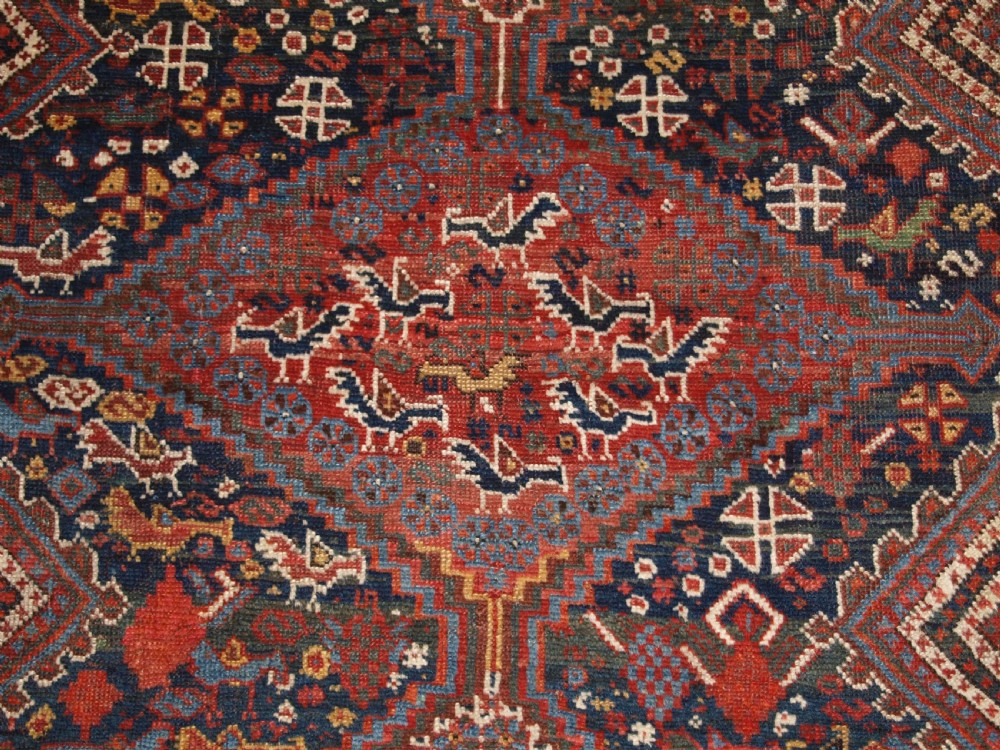 An antique hand-knotted Persian Khamseh wool rug featuring triple diamond medallions filled with stylized bird motifs on a dark navy and red geometric field. View VII