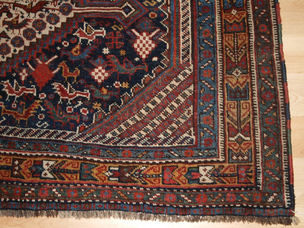 An antique hand-knotted Persian Khamseh wool rug featuring triple diamond medallions filled with stylized bird motifs on a dark navy and red geometric field. View IX