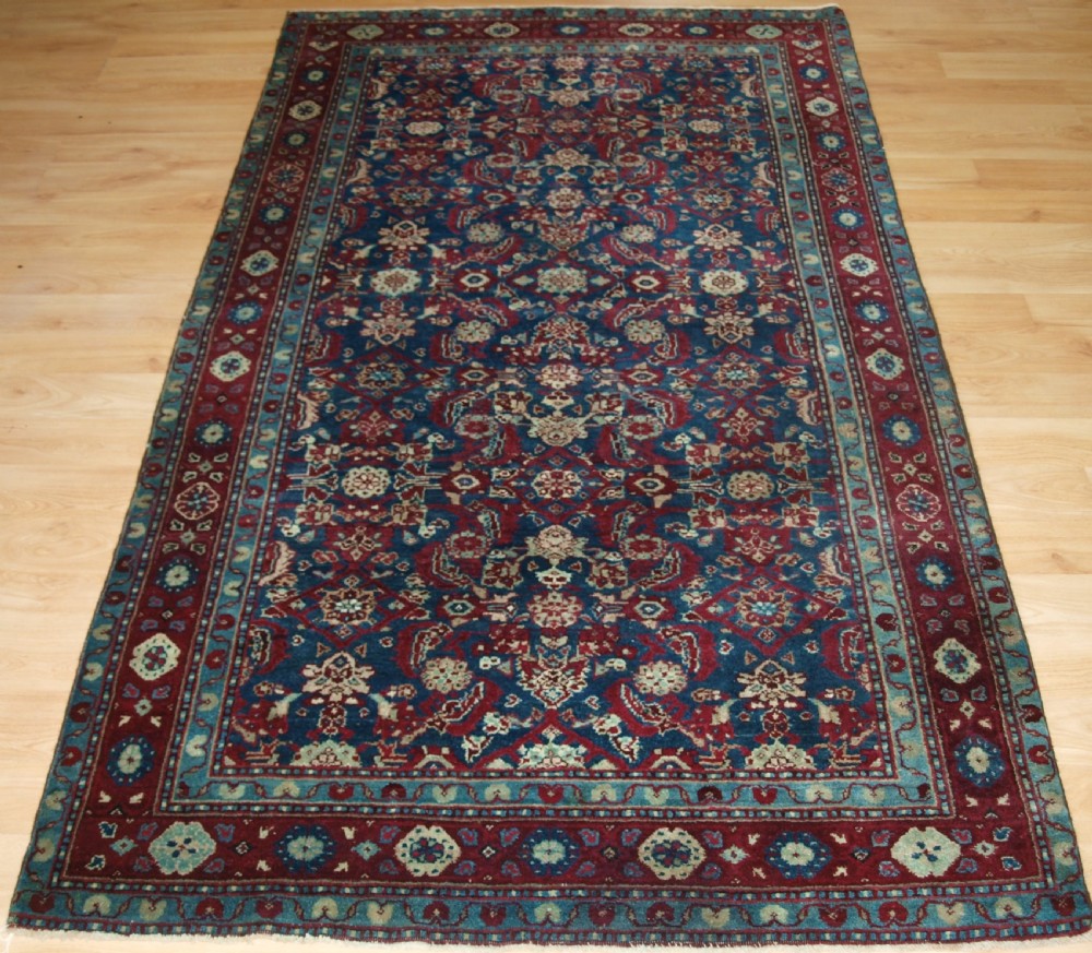 A late 19th-century hand-knotted Indian Agra carpet featuring an intricate all-over floral pattern on a deep blue field with a wide crimson border.