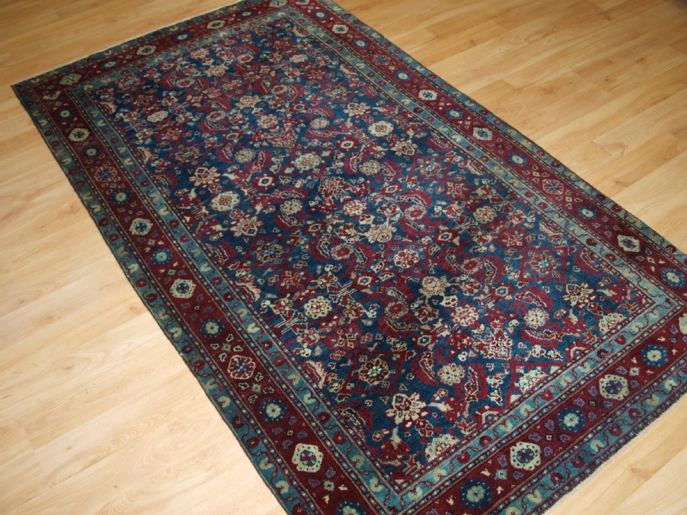 A late 19th-century hand-knotted Indian Agra carpet featuring an intricate all-over floral pattern on a deep blue field with a wide crimson border. View II