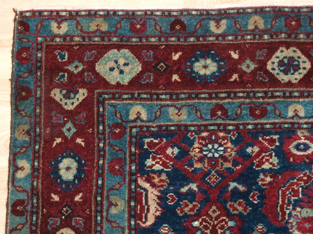 A late 19th-century hand-knotted Indian Agra carpet featuring an intricate all-over floral pattern on a deep blue field with a wide crimson border. View III