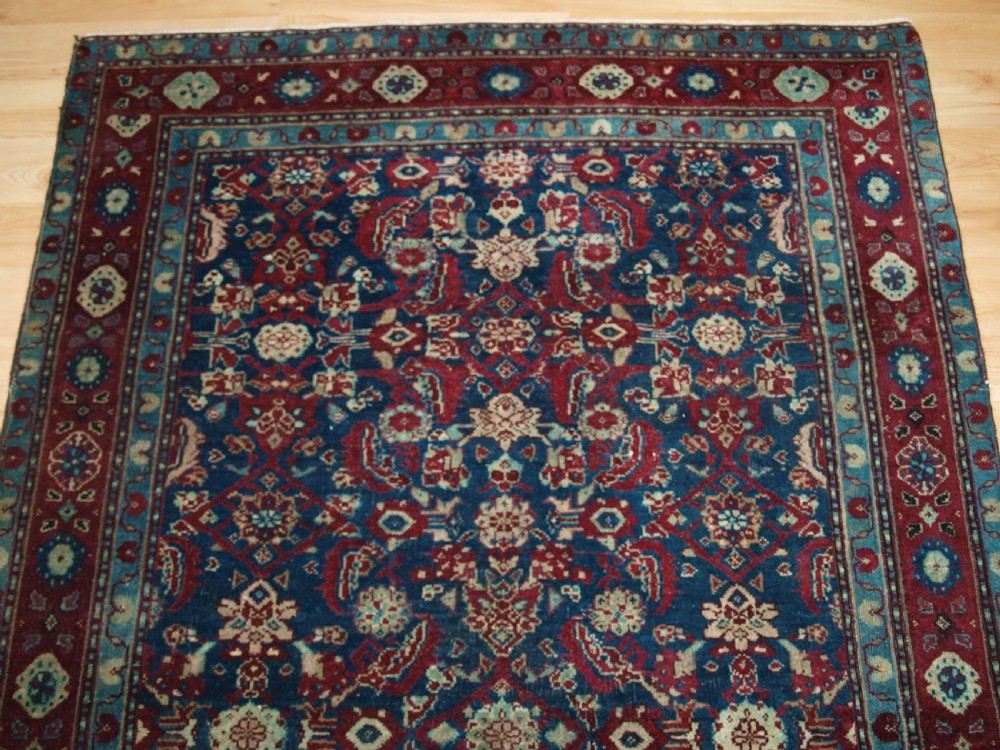 A late 19th-century hand-knotted Indian Agra carpet featuring an intricate all-over floral pattern on a deep blue field with a wide crimson border. View IV
