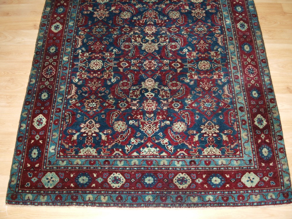 A late 19th-century hand-knotted Indian Agra carpet featuring an intricate all-over floral pattern on a deep blue field with a wide crimson border. View VI