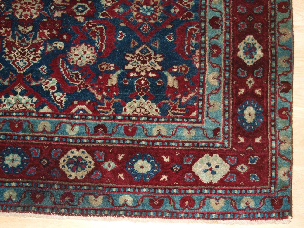 A late 19th-century hand-knotted Indian Agra carpet featuring an intricate all-over floral pattern on a deep blue field with a wide crimson border. View IX