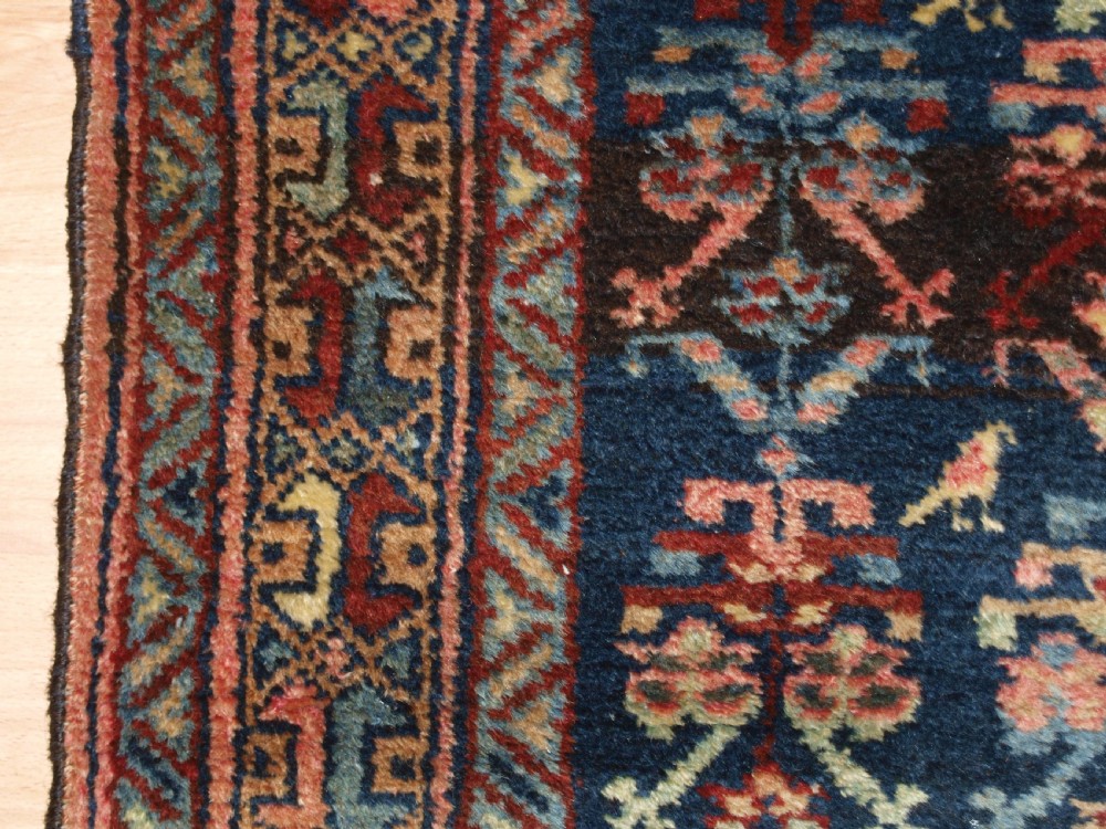 A long narrow antique Luri wool runner carpet with repeating colourful geometric tribal motifs on a dark indigo background framed by decorative multi-band borders. View III