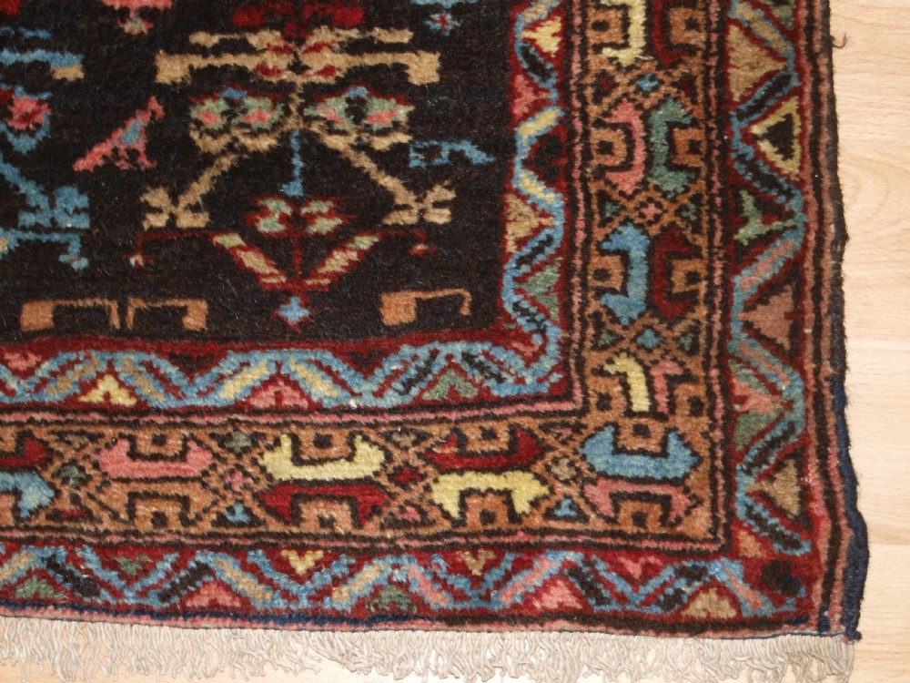 A long narrow antique Luri wool runner carpet with repeating colourful geometric tribal motifs on a dark indigo background framed by decorative multi-band borders. View IX
