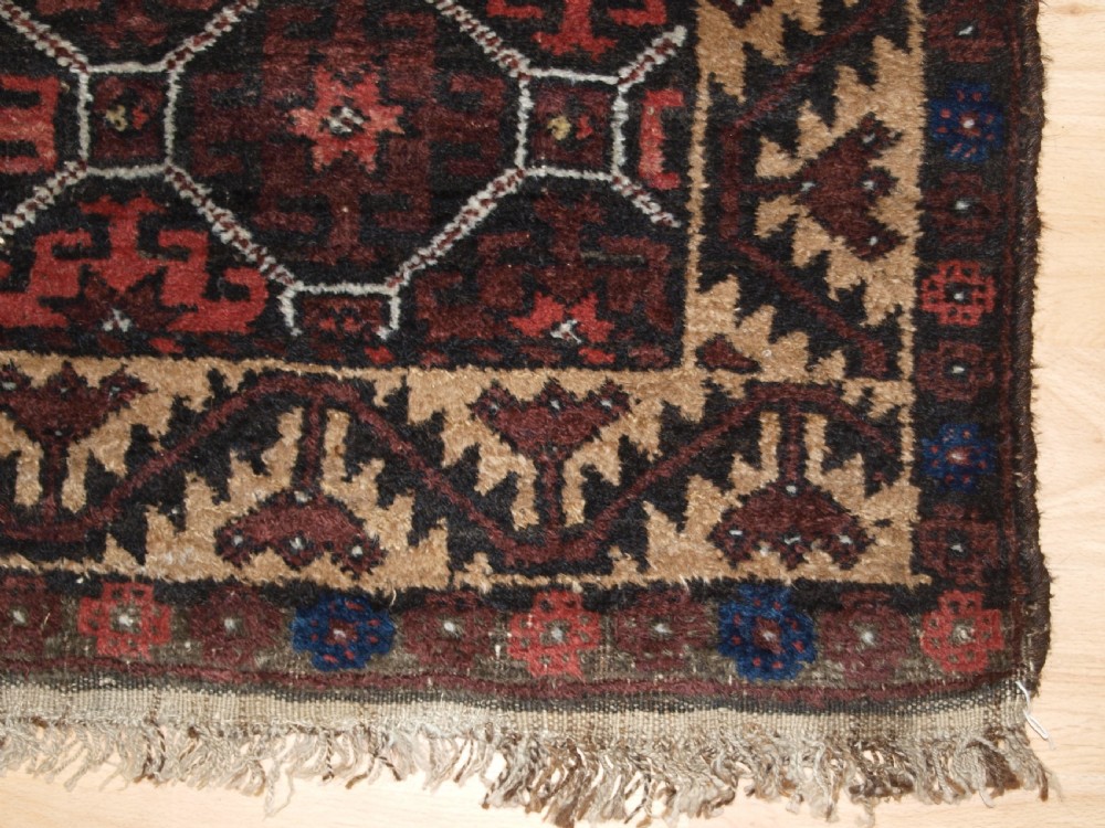 An antique Afghan Baluch wool rug featuring a dark red and brown diamond lattice design framed by geometric serrated borders. View VIII