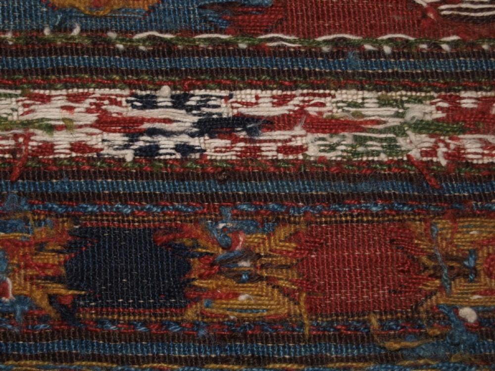 A rectangular hand-woven antique Caucasian Soumak wool panel featuring horizontal bands with geometric diamond medallions in terracotta red, navy blue, ivory, and green. View VII