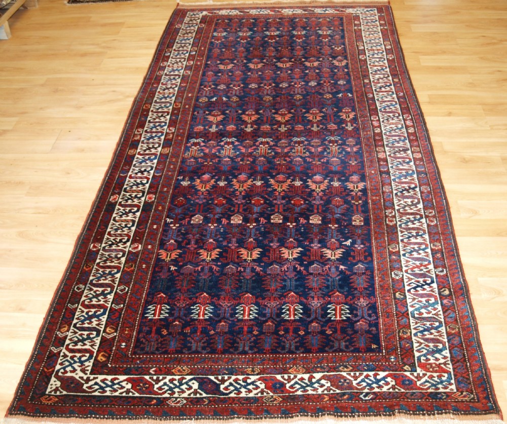 An antique hand-knotted Kurdish Kelleh long rug featuring a deep navy central field with geometric motifs enclosed by an ivory dragon pattern border.