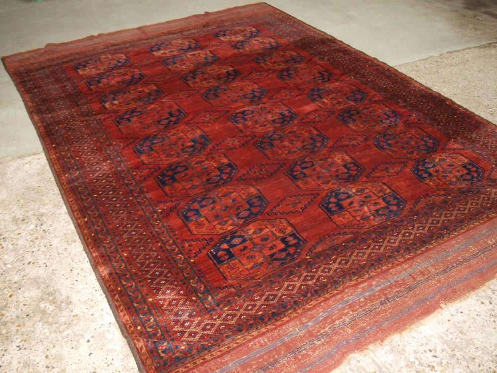 A large hand-knotted antique Ersari Turkmen carpet featuring octagonal gul motifs on a terracotta red wool field.