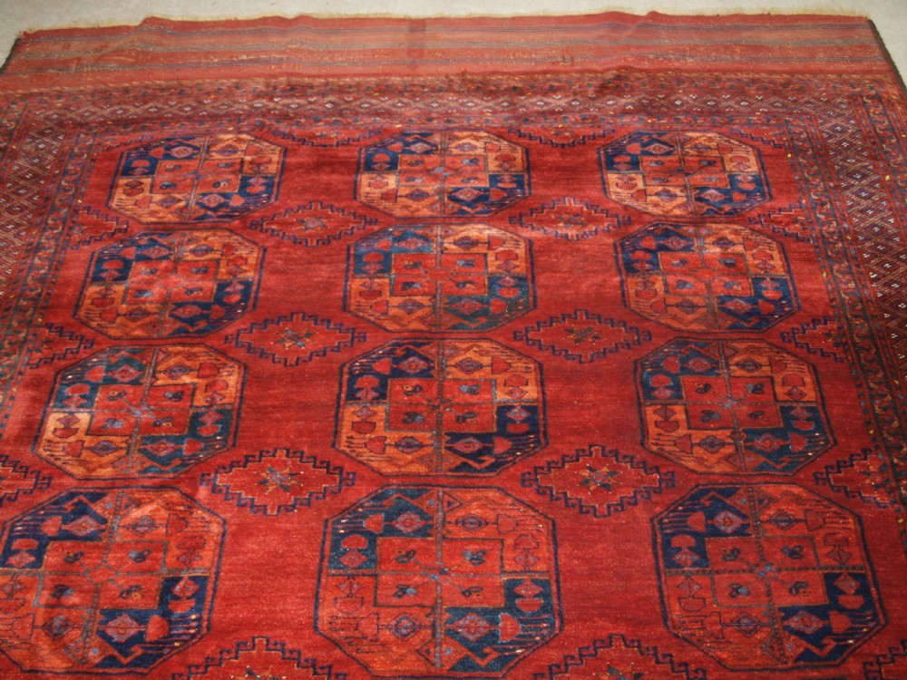 A large hand-knotted antique Ersari Turkmen carpet featuring octagonal gul motifs on a terracotta red wool field. View IV