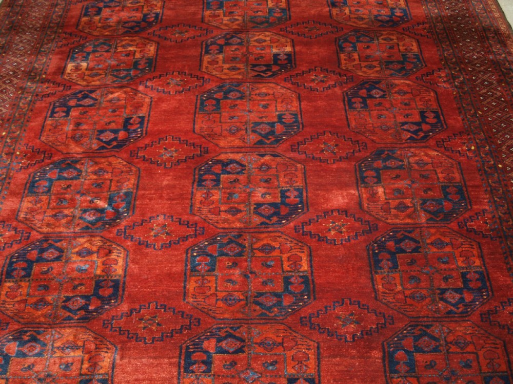 A large hand-knotted antique Ersari Turkmen carpet featuring octagonal gul motifs on a terracotta red wool field. View V