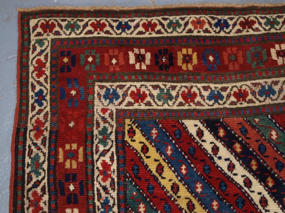 An antique handwoven wool Caucasian Gendje rug runner featuring diagonal polychrome stripes framed by multiple geometric borders. View III