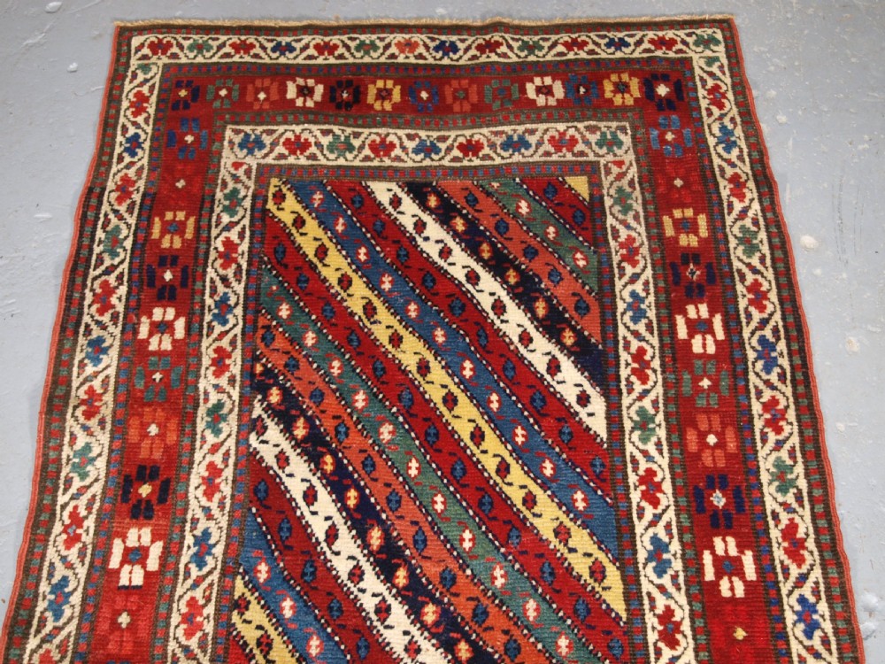An antique handwoven wool Caucasian Gendje rug runner featuring diagonal polychrome stripes framed by multiple geometric borders. View IV