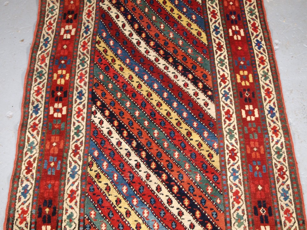 An antique handwoven wool Caucasian Gendje rug runner featuring diagonal polychrome stripes framed by multiple geometric borders. View VI