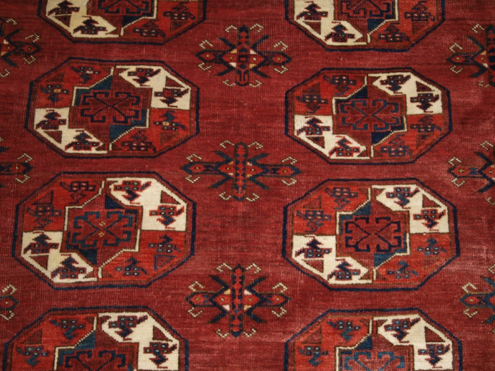 An antique red hand-knotted wool carpet displaying repeated octagonal gul motifs, geometric borders, and woven flatweave ends. View VIII