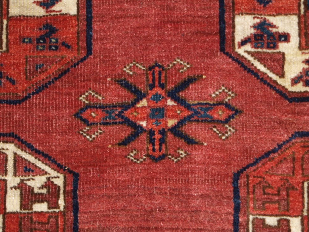 An antique red hand-knotted wool carpet displaying repeated octagonal gul motifs, geometric borders, and woven flatweave ends. View XI