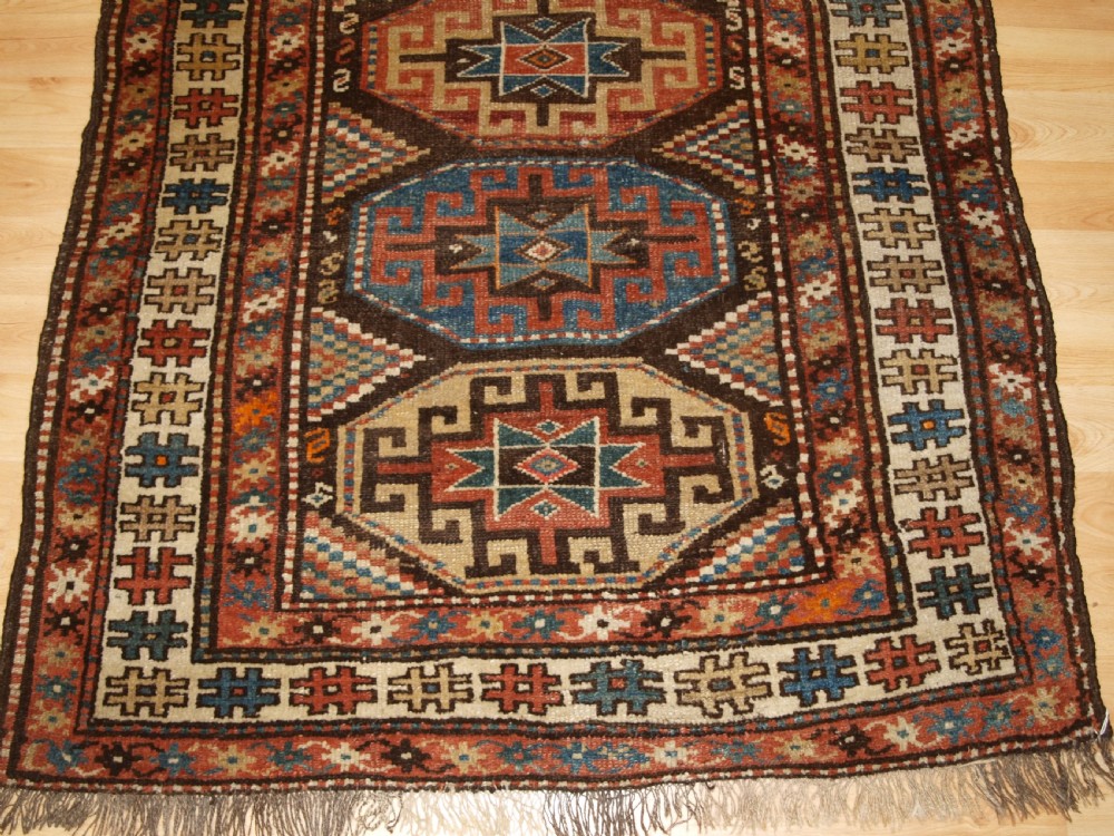 An antique hand-knotted Kurdish runner rug featuring a vertical sequence of octagonal Memling gul motifs in terracotta, blue, and cream shades. View VI