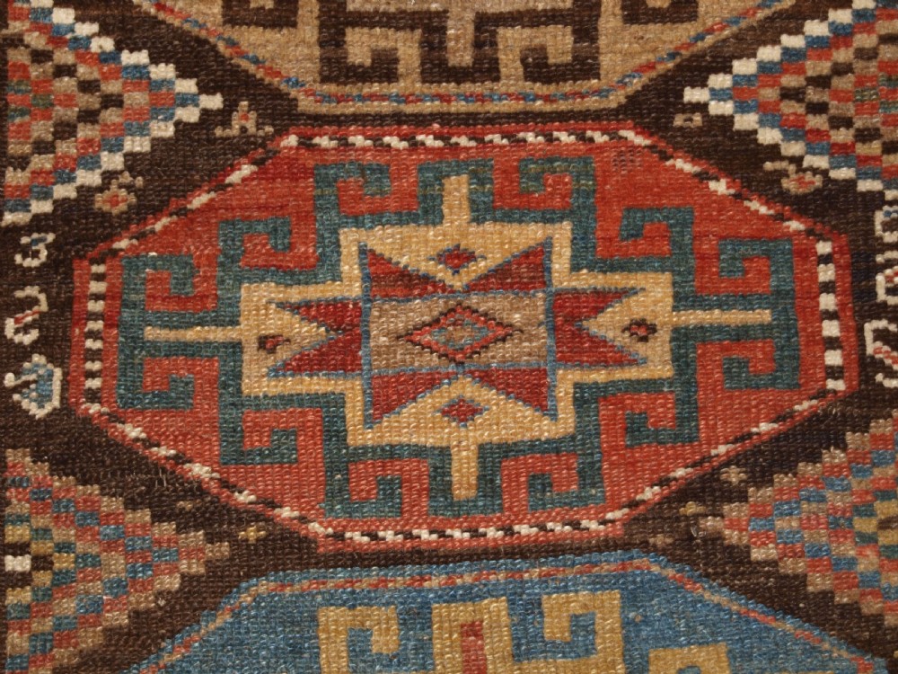An antique hand-knotted Kurdish runner rug featuring a vertical sequence of octagonal Memling gul motifs in terracotta, blue, and cream shades. View VIII