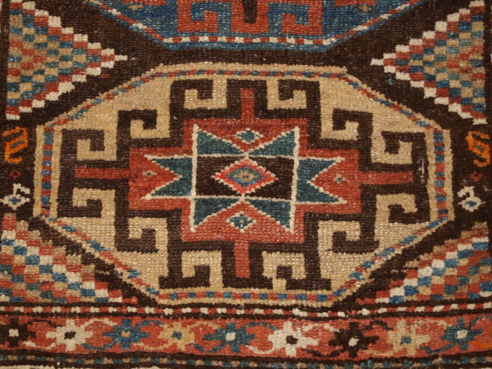 An antique hand-knotted Kurdish runner rug featuring a vertical sequence of octagonal Memling gul motifs in terracotta, blue, and cream shades. View IX