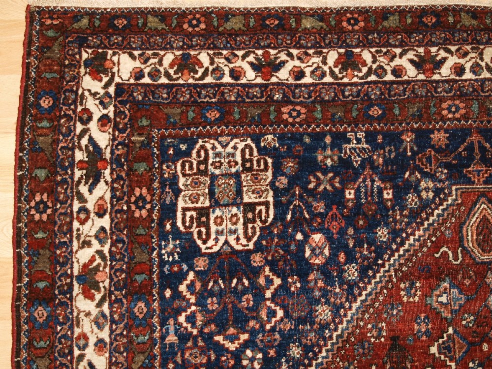 An antique hand-knotted Persian Abedeh rug featuring a central cream diamond medallion surrounded by a terracotta red field with navy blue corners. View II