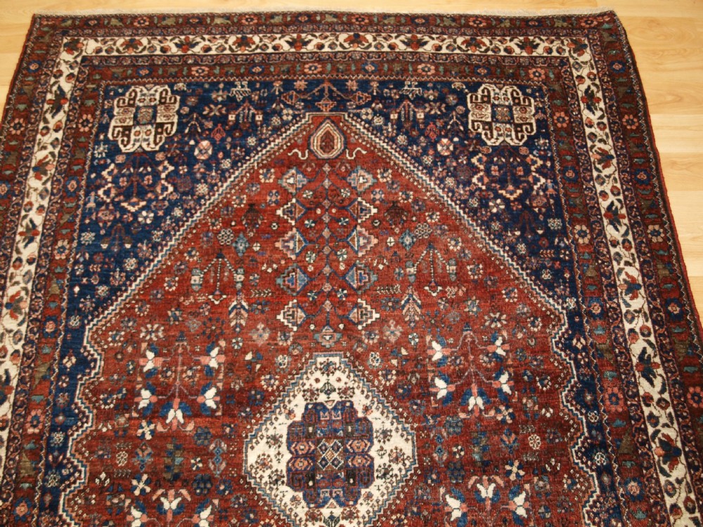 An antique hand-knotted Persian Abedeh rug featuring a central cream diamond medallion surrounded by a terracotta red field with navy blue corners. View IV