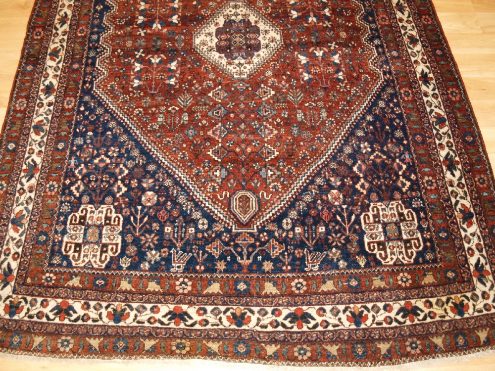 An antique hand-knotted Persian Abedeh rug featuring a central cream diamond medallion surrounded by a terracotta red field with navy blue corners. View VI