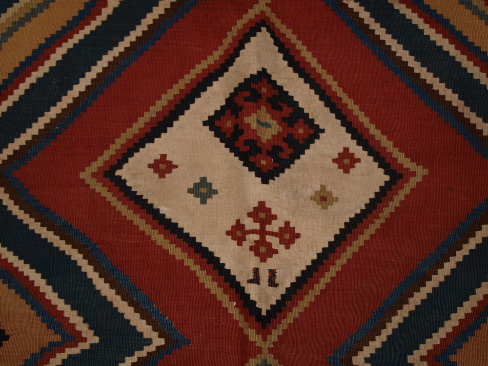 An antique flatweave Qashqai wool kilim rug featuring bold geometric diamond and chevron eye-dazzler patterns in terracotta red, indigo blue, cream, and brown. View VII
