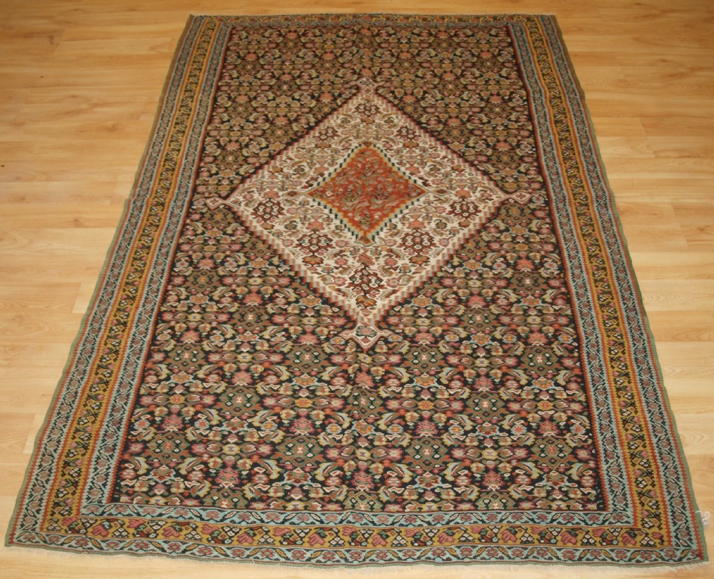 ANTIQUE SENNEH KILIM, SINGLE MEDALLION WITH HERATI, CIRCA 1900.